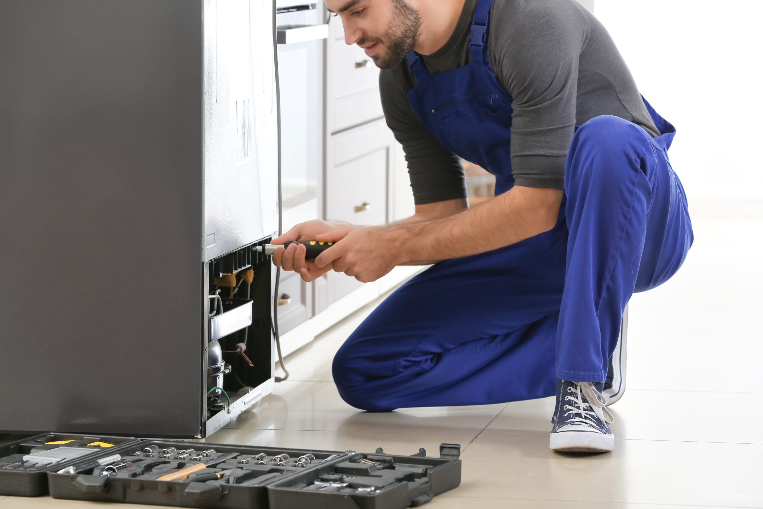 Male technician repairing refrigerator indoors Plumbers Winnipeg